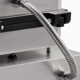 Metallic hose attached to a piece of industrial equipment on a gray background